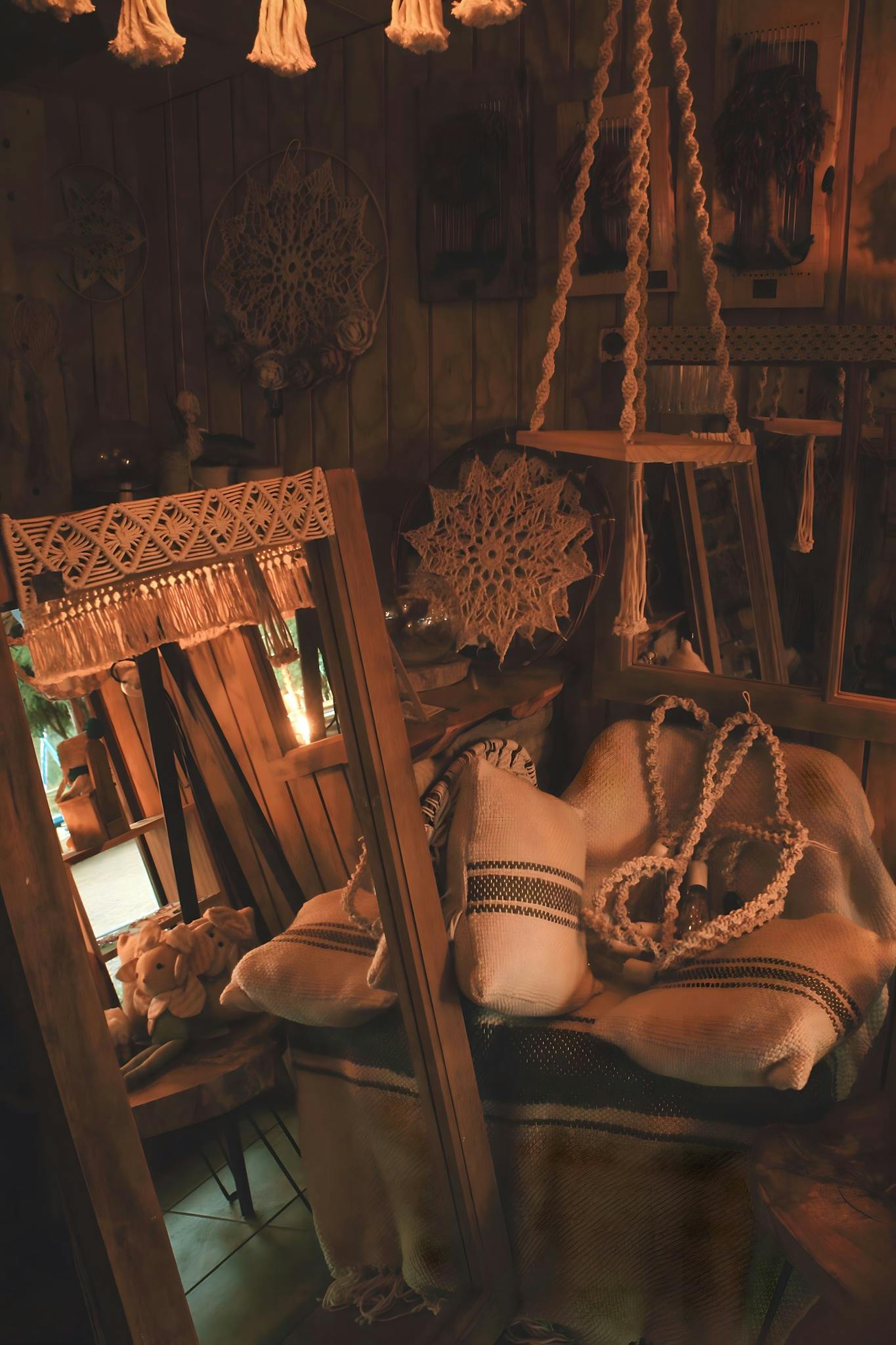 Warm rustic room with macramé decor, cushions, and wooden elements.